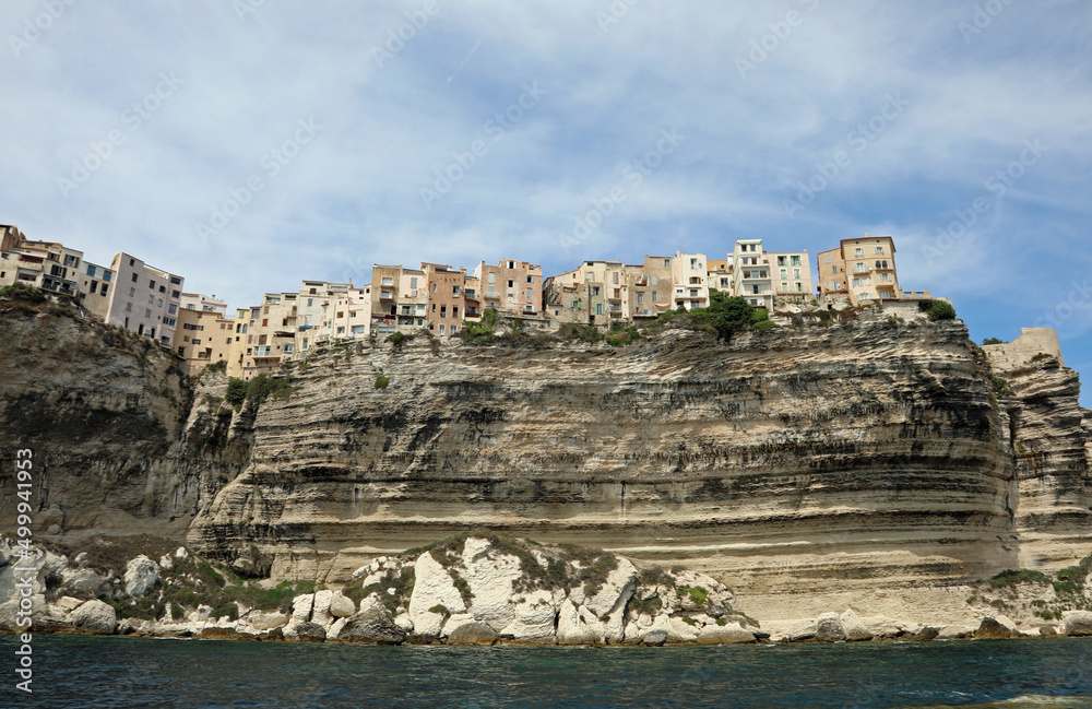 houses perched on the cliff overlooking the sea of the village BONIFACIO in the island of Corsica seen from the sea