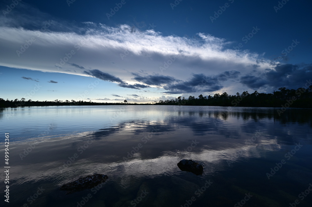 Beautiful late afternoon cloudscape over Pine Glades Lake in Everglades National Park, Florida reflected in lake's calm water.