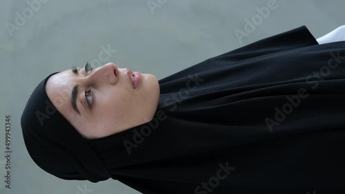 Vertical video of an Arab woman wearing a black hijab. Religious fanatics of the Islamic world force women to wear hijabs to hide their appearance from prying male eyes. photo