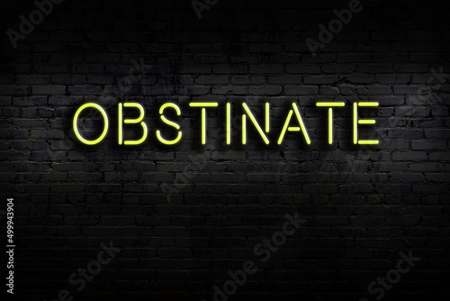 Night view of neon sign on brick wall with inscription obstinate
