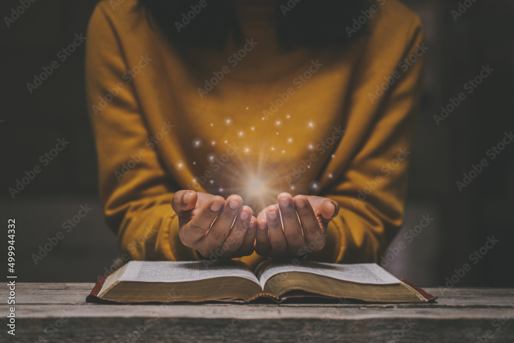 Woman praying on holy bible in the morning have a Yellow lights and  sparkles coming. Woman hand with Bible praying. Christian life crisis prayer  to god. Stock-bilde | Adobe Stock