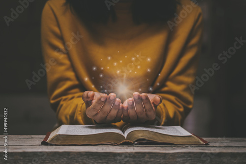 Slika na platnu Woman praying on holy bible in the morning have a Yellow lights and sparkles coming