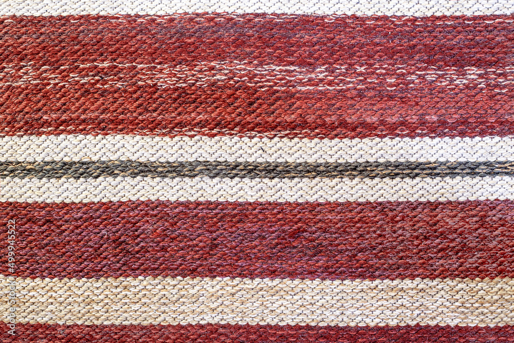 Traditional woven rug shades of red motley.  rustic mat