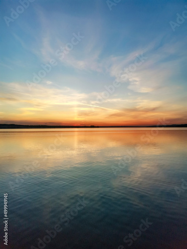 Sunset on a pond with blue sky, red clouds and water with reflection. Russia.