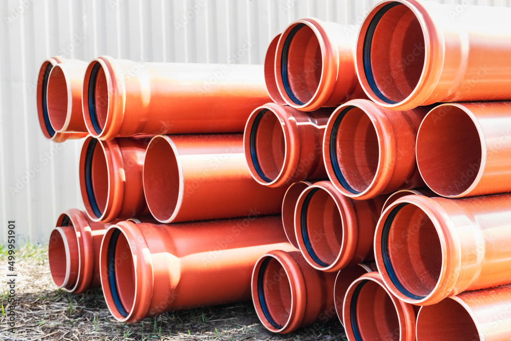 Orange sewer pipes at the construction site. Preparation for the installation of an underground sewer system. Wastewater disposal. Orange sewer pipes at the construction site. Preparation for the installation of an underground sewer system. Wastewater disposal.