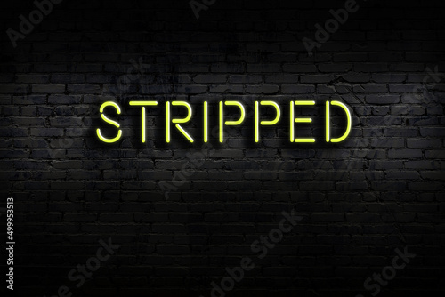 Night view of neon sign on brick wall with inscription stripped