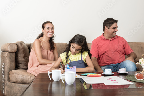 Casal brasileiro ajudando filha com dever de casa na sala de estar