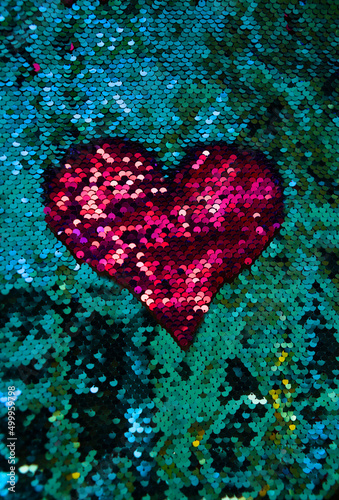 Pink heart on a green background. Embroidery on a jacket made of sequins in the form of a pink heart. Needlework and embroidery on a jacket.