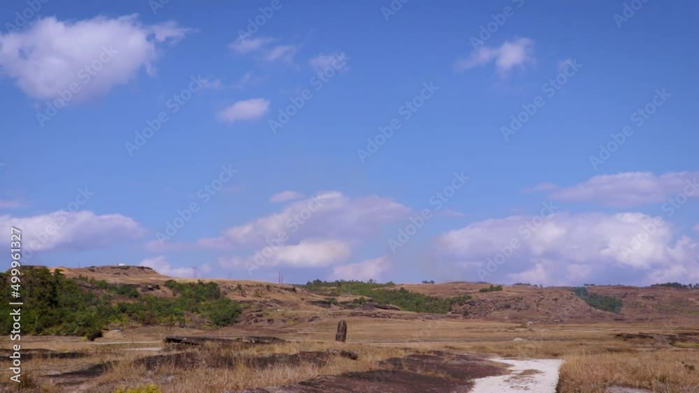 yellow grass mountain with leading trails and bright blue sky at day yellow grass mountain with leading trails and bright blue sky at day