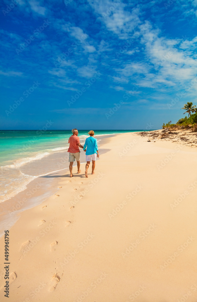 Loving retired couple walking on beach leaving footprints Loving retired couple walking on beach leaving footprints