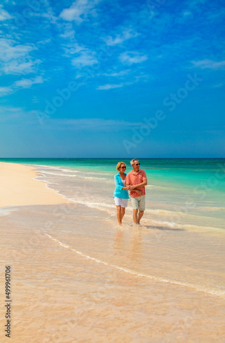 Retired couple in casual clothing walking on beach
