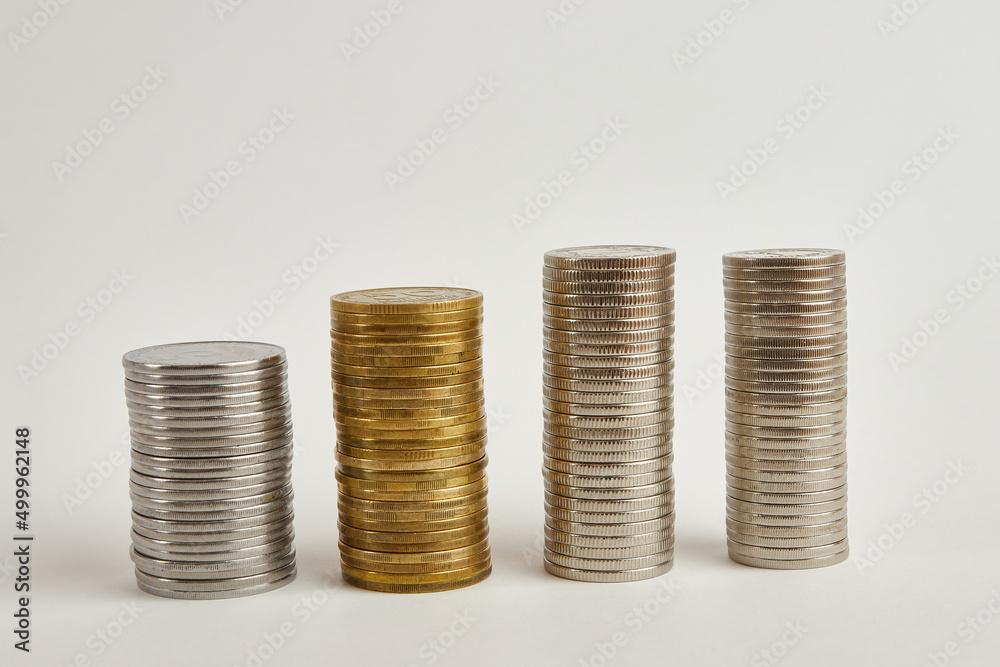 Four towers with coins of different denominations on a white background. Four towers with coins of different denominations on a white background.