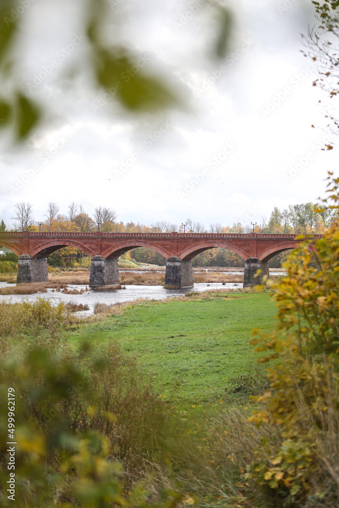 Autumn weather view of old red brick over Venta river in small countryside city Kuldiga, Latvia.