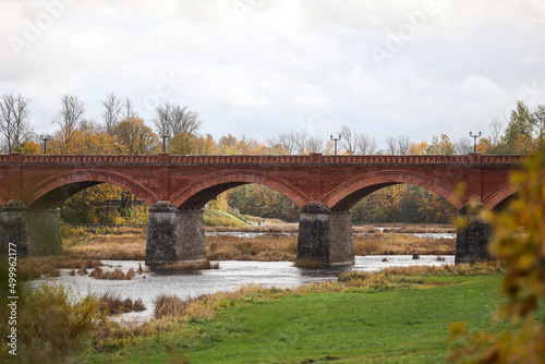 Autumn weather view of old red brick over Venta river in small countryside city Kuldiga, Latvia.