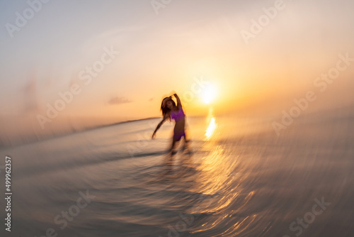 Motion blurred ocean sunrise with dancing Asian girl
