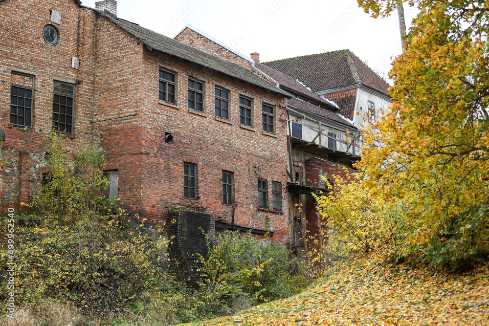 Obraz premium Old countryside brick building house with yellow leaves near.