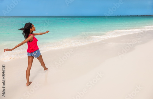 Afro American girl walking barefoot by tropical ocean