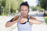 tired female runner taking pulse and looking at smartwatch