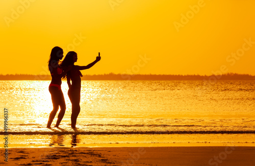 Tropical ocean sunrise with friends taking selfies silhouette