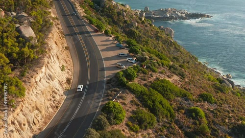 Vehicles Driving Along Victoria Road With Ocean Views Near Oudekraal, South Africa. - aerial photo