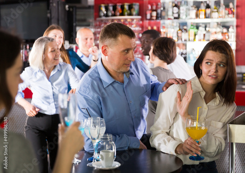 Unhappy woman refusing man who wants to talk with her on corporate party