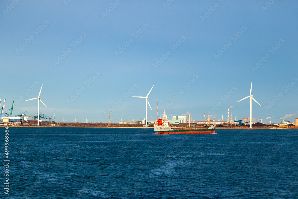 Wind turbines and an offshore cargo ship in the bay of the seaport of Fos-sur-Mer, France.