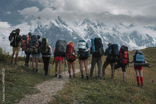 A group of tourists with backpacks admire the view of the main ridge of the Caucasus, Svaneti, Georgia photo