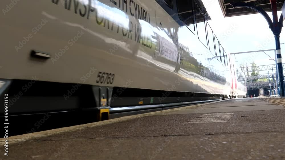 Low angle view of shiny passenger train arriving and stopping at the platform in Stockport town in Greater Manchester.