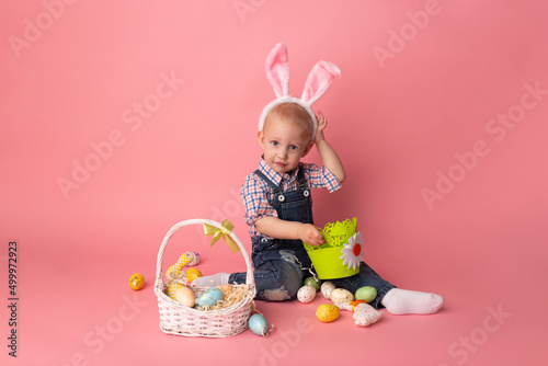 Cute little boy with bunny ears and easter eggs on pink background. Happy Easter