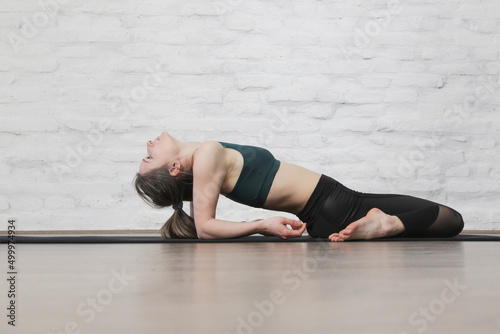Young woman practicing stretching yoga positions. Wellbeing and self care concept.