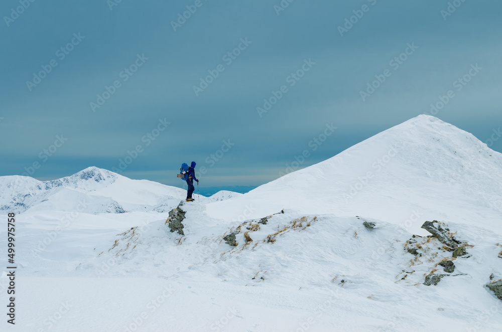 Climber looking at majestic snowcapped mountain peak in winter landscape

