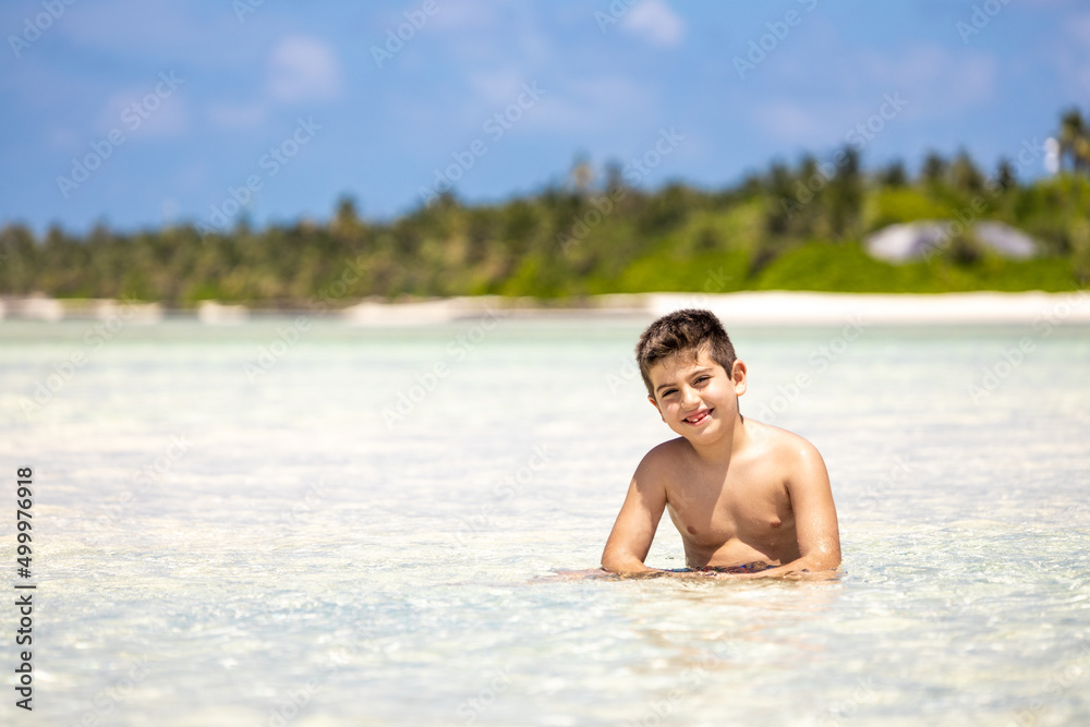 Cute boy inside the water ona white sand beach