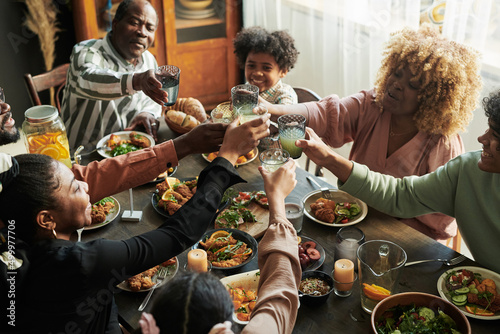 Canvas Print African big family toasting with glasses with lemonade while having holiday dinn