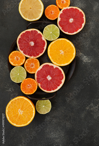 cut colored citrus fruits on a dark background, orange, grapefruit, tangerine © lokisurina