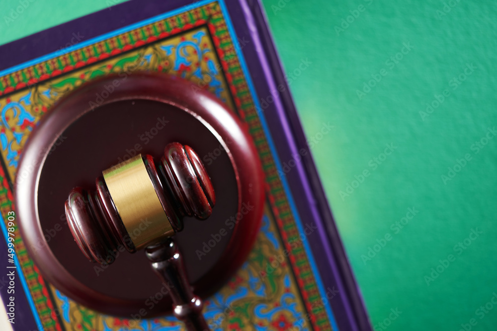 Sharia or Islamic law concept with gavel and koran on green background