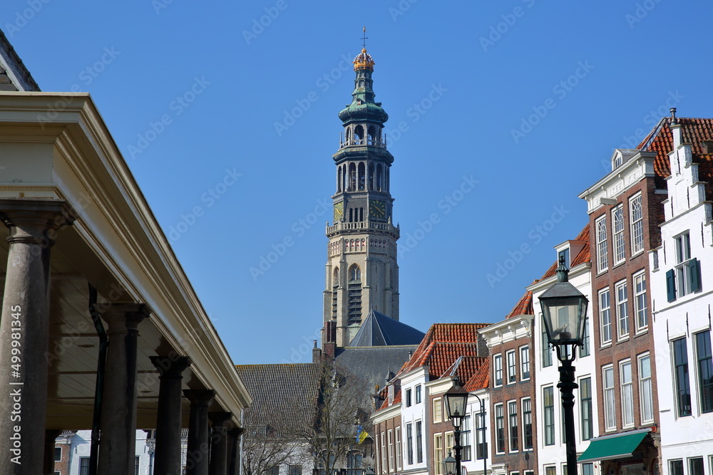The impressive Abdijtoren de Lange Jan (Long John Abbey tower) viewed from the Dam street in Middelburg, Zeeland, Netherlands, with historic buildings in the foreground