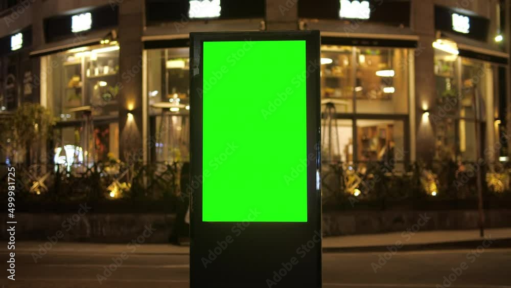 Billboard with a green screen on a background of city traffic in night time