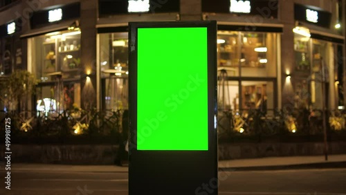 Billboard with a green screen on a background of city traffic in night time