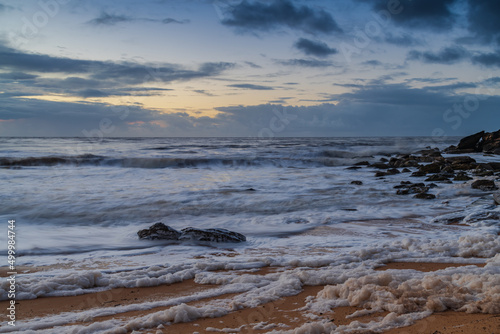 Sunrise seascape with sea foam and rain clouds © Merrillie