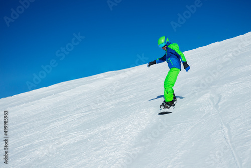 Snowboarder boy go downhill with snowboard on ski slope