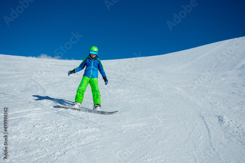 Front view action photo of boy snowboard down mountain slope