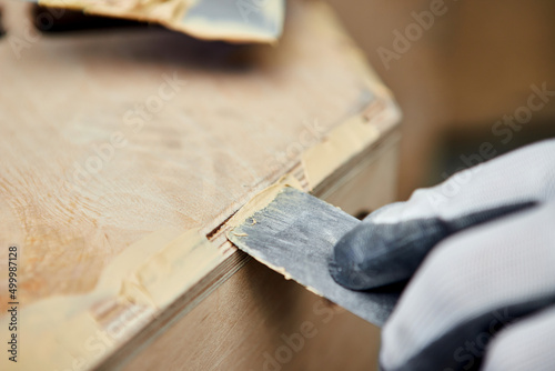 Putty of wood. Manual worker spackling wooden products at the carpentry manufacturing. Close up of working process photo