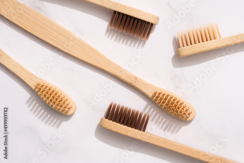 Closeup view of bamboo toothbrushes with natural bristle on white marble table background. Mockup  selective focus