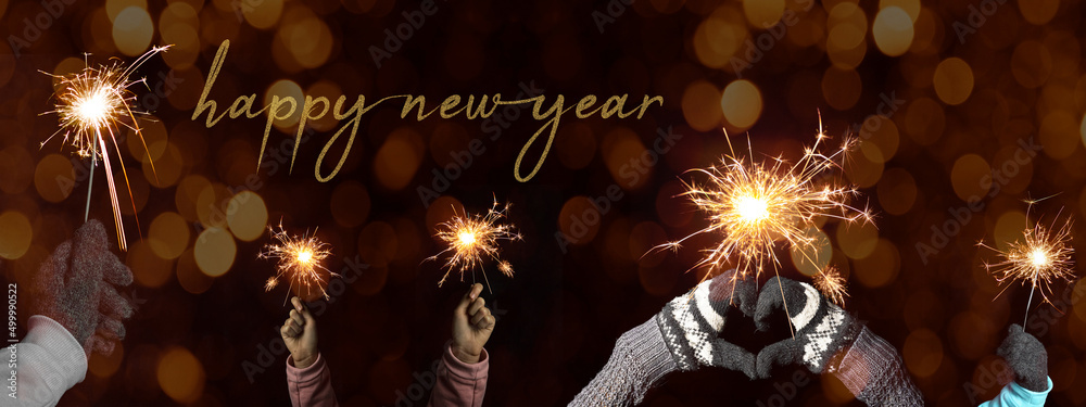 Happy New Year 2023 background banner greeting card - Young family with two  children holding sparkling sparklers in her hands at dark night, with  orange bokeh lights Stock Photo | Adobe Stock