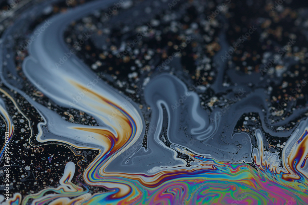 Shallow depth of field close up, image of the surface of a bubble. The soap is swirling around suspended on the surface of the bubble with reflected and refracted colours.