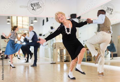 Woman pensioner with african man practising charleston photo