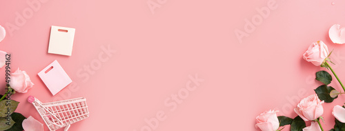 Mother's Day shopping design concept background with pink rose flower and cart on pink background. © RomixImage