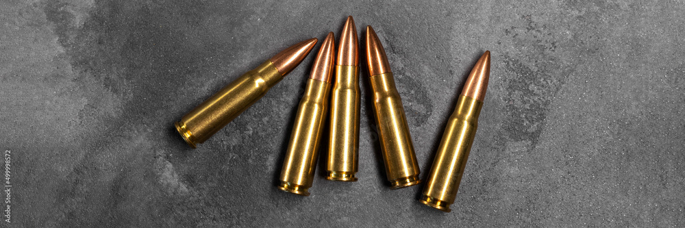 Bullets on gray background banner. Cartridges 7.62 caliber for Kalashnikov assault rifle. Panoramic web header. Wide screen wallpaper Bullets on gray background banner. Cartridges 7.62 caliber for Kalashnikov assault rifle. Panoramic web header. Wide screen wallpaper