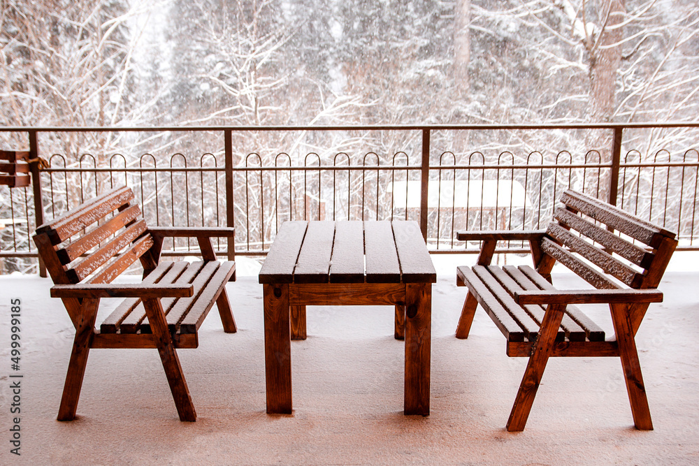 A table and benches in the snow on a snow-covered veranda.