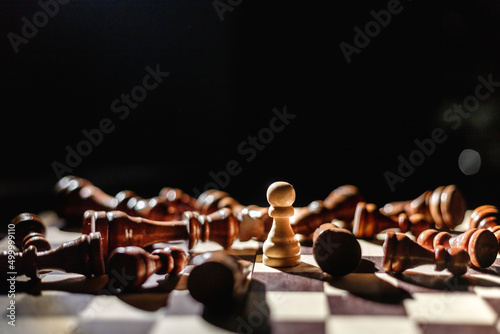 Winner white pawn surrounded by lying black chess. Leadership, strength and confidence concept